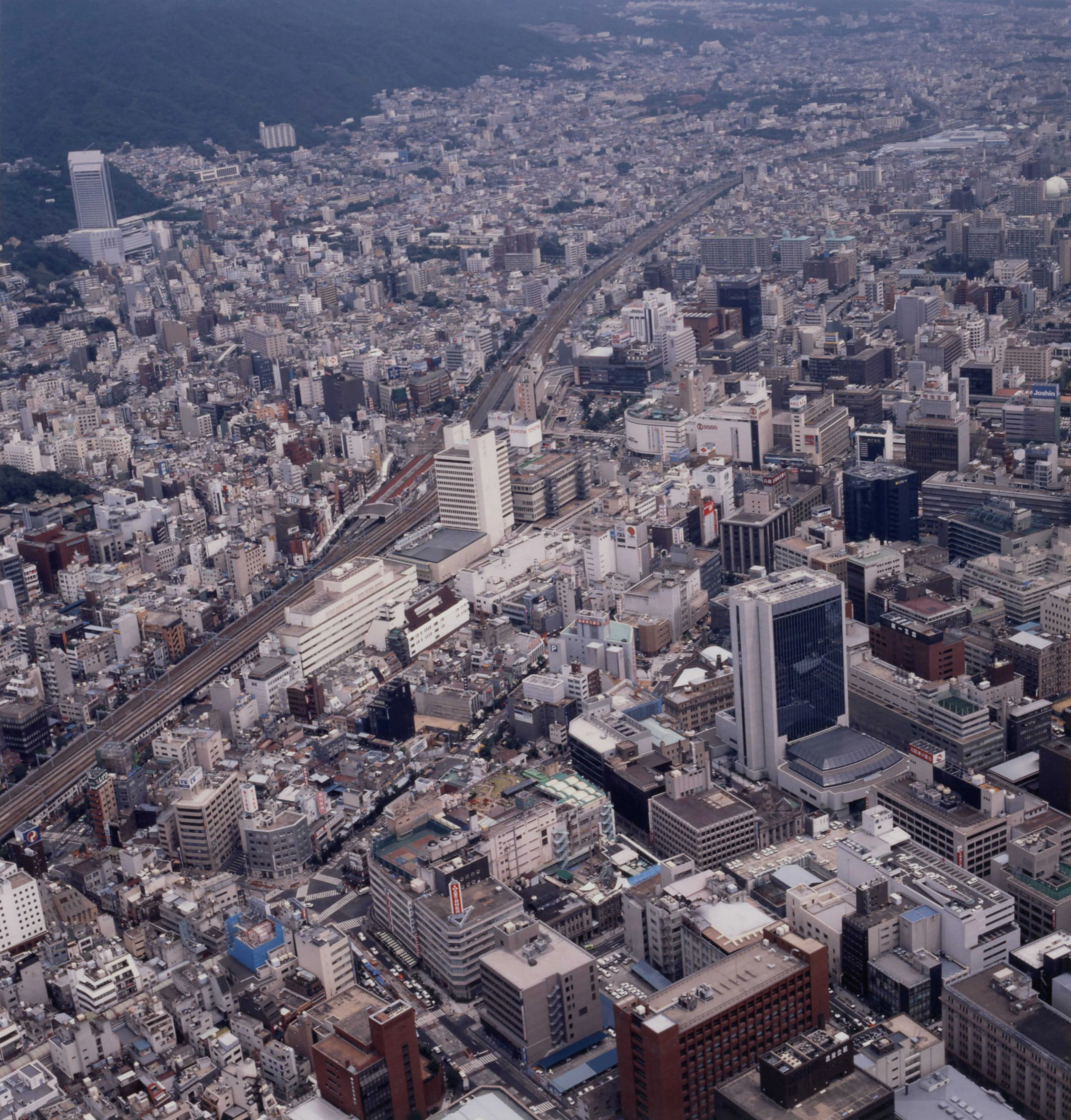 空撮写真。高いビルや大きな道路があるカラー写真。下に写真の説明あり。