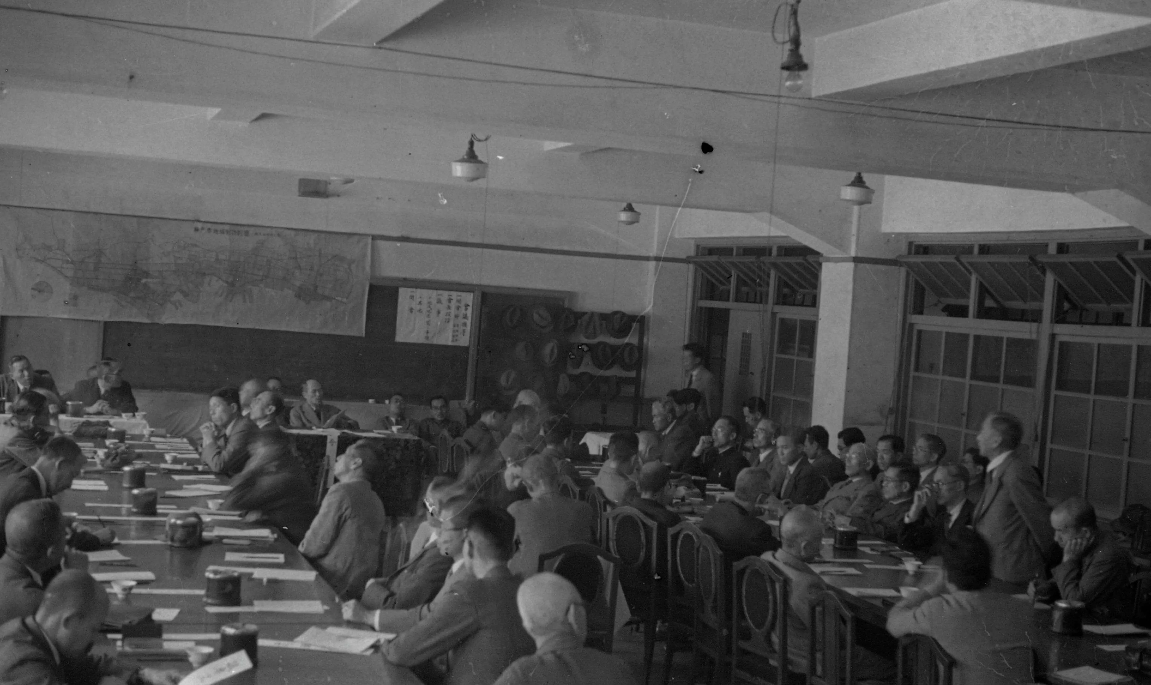 復興計画策定の委員会の様子の写真。長机の左右に多くの人たちが座っている様子が写っている。下に写真の説明あり。