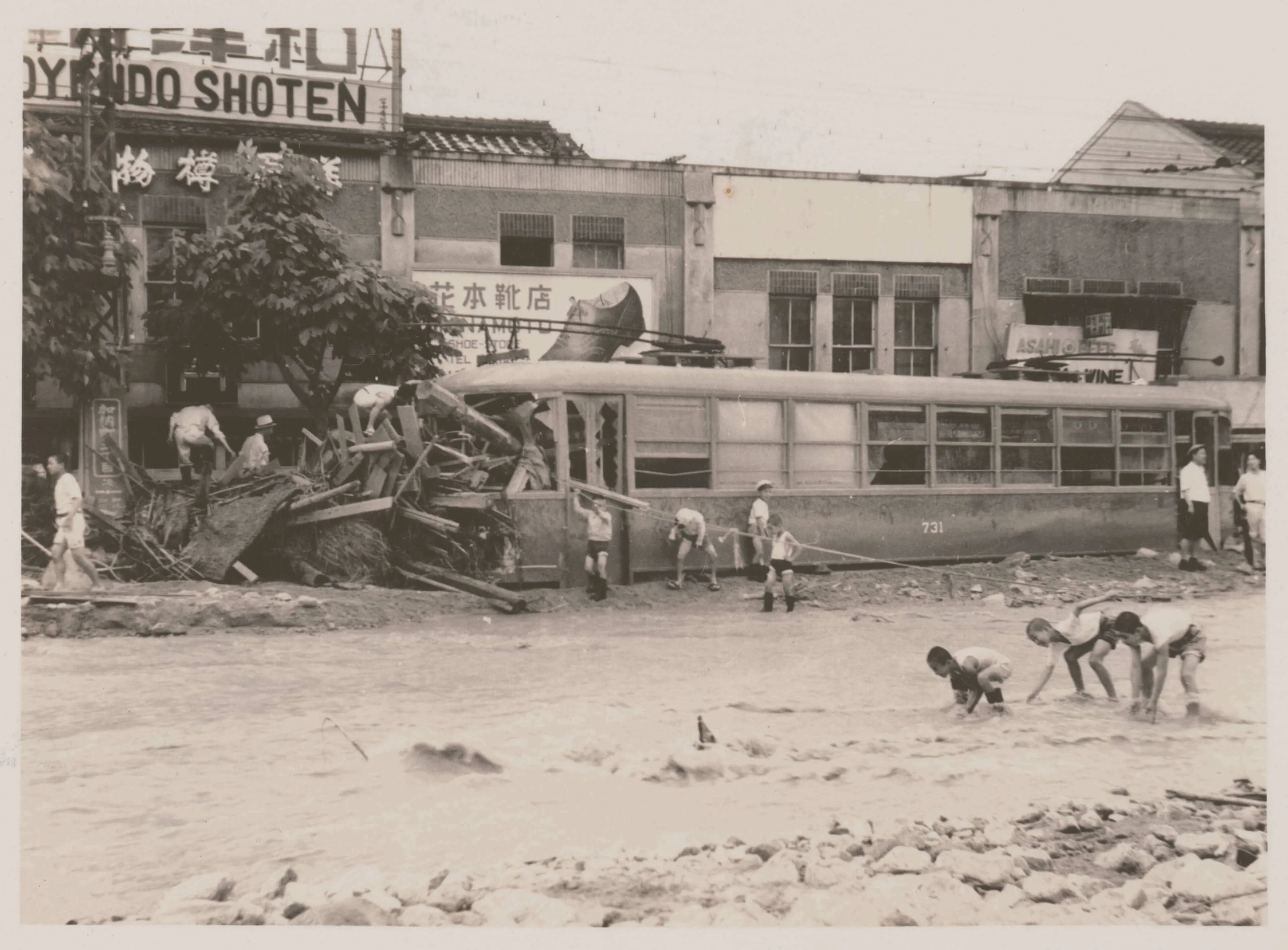 1938年に起きた阪神大水害で、道が川となっている加納町3丁目交差点。道を渡るために綱が張られている。瓦礫に潰された市電の車両。